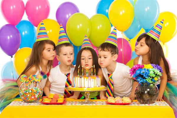 گروهی از بچه های کوچک شاد که جشن تولد را جشن می گیرند و شمع ها را روی کیک می دمند مفهوم تعطیلات
