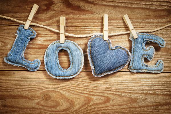 کلمه عشق به انگلیسی ساخته شده از حروف شلوار جین روی طناب روی زمینه چوبی جذاب است مفهوم روز سنت ولنتاین