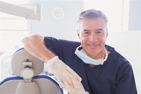 نزدیک شدن دندانپزشک خندان و خم به صندلی دندانپزشکان در کلینیک دندانپزشکی