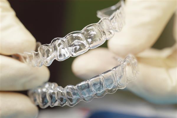 عکسبرداری از نمای نزدیک دستان پزشکان در دستکشهایی که محافظ دهان سیلیکونی دارند مراقبت از دندان