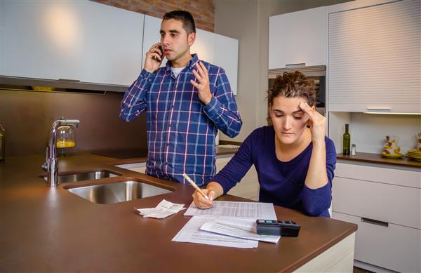 مرد جوان عصبانی در حالی که زنی خط اعتباری بانکی خود را محاسبه می کند در حال بحث و جدال با تلفن است مفهوم مشکلات مالی خانواده