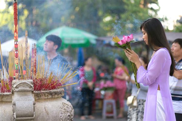 دختر ویتنامی که در معبد بودایی مشغول نماز است و گلهای نیلوفر آبی را در دست دارد سایگون ویتنام