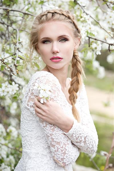 زن جوان و زیبای بور در باغ شکوفه عروس