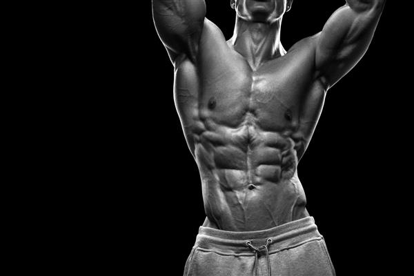 مدل مرد تناسب اندام و بدنساز جوان عضلانی و متناسب که از پس زمینه سیاه استفاده می کند عکس سیاه و سفید با فضای کپی
