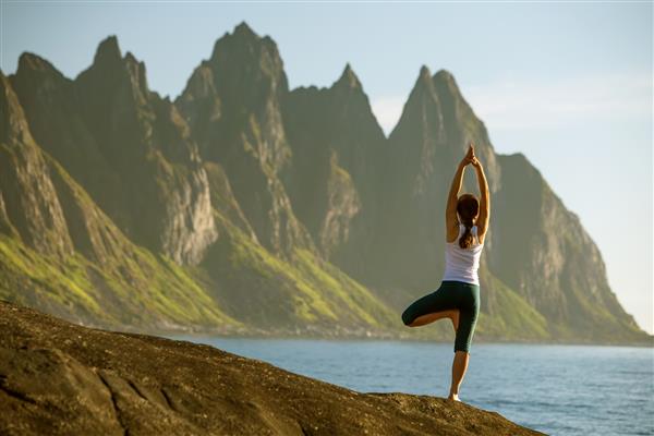زن جوان در نروژ در حال تمرین یوگا بین کوه ها است