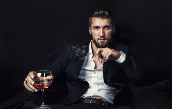 مردی جذاب با یک سیگار برگ و یک لیوان شراب در دستانش