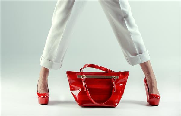 پاهای زنانه زیبا در کفش و کیف قرمز