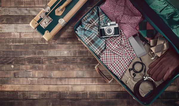 چمدان آماده جذاب مسافرتی همراه با دوربین و لباس فضای کپی خالی نمای بالا