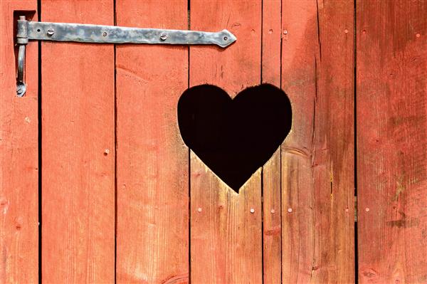 درب چوبی در فضای باز با قلب حک شده زیر لولای آهنی در اسکاندیناوی قلب همچنین به عنوان دریچه یا سوراخ بازرسی عمل می کند