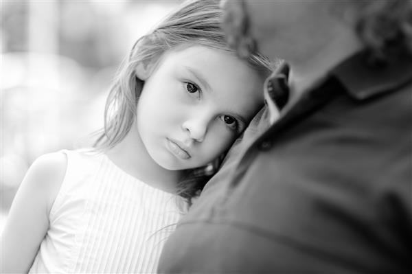 عکس سیاه و سفید دختر کوچک غمگین در کنار پدرش