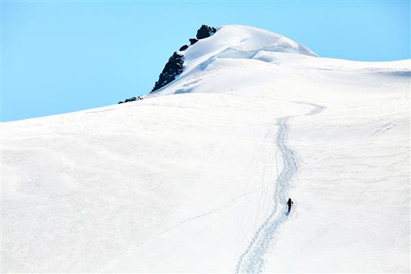کوهنوردان در بالای یک گردنه با کوله پشتی هایی که در کوهستان با طلوع آفتاب ملاقات می کنند