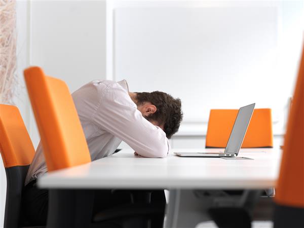 مرد جوان تاجر ناامید دارای مشکلات استرس است نشستن به تنهایی در اتاق جلسات دفتر و کار بر روی محاسبات لپ تاپ