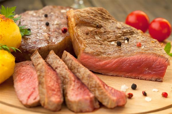 استیک گوشت گاو با فلفل قرمز و سیاه روی تخته چوبی