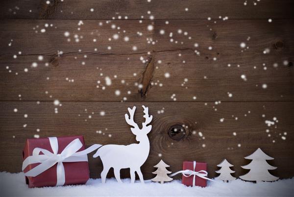 تزیین کریسمس با هدایای قرمز یا درختان گوزن یا گوزن های شمالی و درختان کریسمس را روی برف هدیه می دهد کارت مخصوص تبریک های فصلی فضا را برای تبلیغات کپی کنید دانه های برف در برابر پس زمینه چوبی قرار دارند