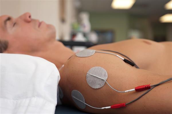 فیزیوتراپی یا درمان کایروپراکتیک شانه آسیب دیده بیمار مرد با استفاده از تحریک الکتریکی مداخله ای از طریق پوست TENS برای مدیریت درد