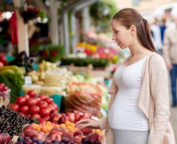 خرید بارداری و مفهوم افراد - زن باردار خوشحال انتخاب غذا در بازار