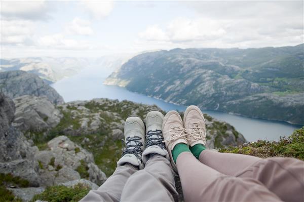 دو زن دوست که روی صخره های نشسته اند نمای منظره تابستان نروژ