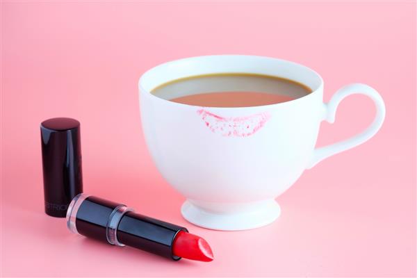 رژ لب قرمز و فنجان قهوه در زمینه صورتی