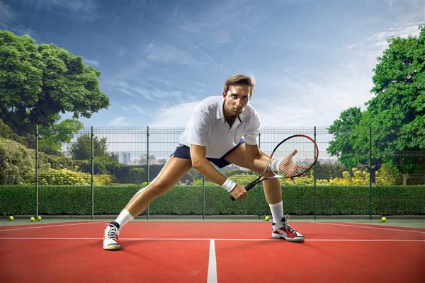 مرد جوانی در روز آفتابی در حال بازی تنیس است