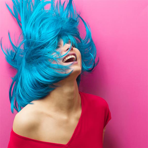 پرتره استودیویی از یک دختر زیبا با موهای فیروزه ای در حرکت در زمینه صورتی