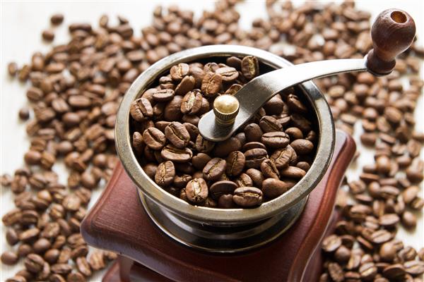 آسیاب قهوه در پس زمینه دانه های قهوه نزدیک