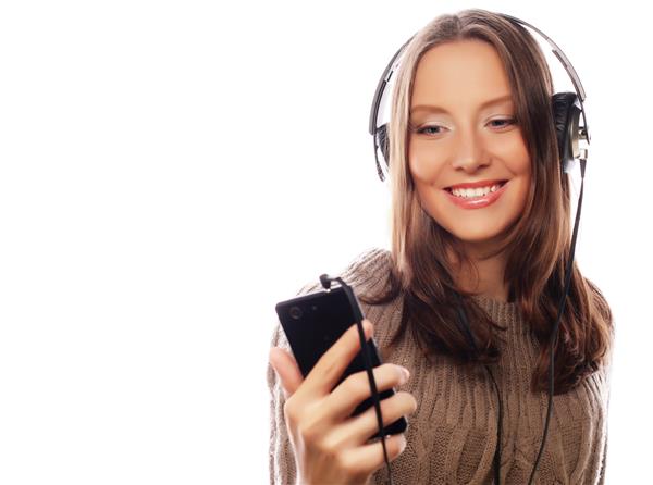 زن جوان شاد با هدفون که از پس زمینه سفید موسیقی گوش می دهد