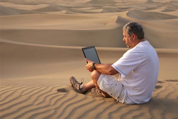 مردی با لپ تاپ که در کویر نشسته است