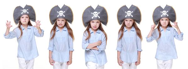 دختر کوچک مثبت با کلاه دزدان دریایی که در تعطیلات روی زمینه سفید