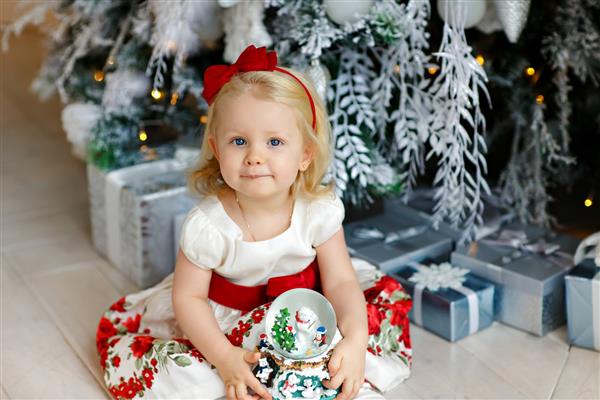 دختر بچه کوچک در کنار درخت کریسمس