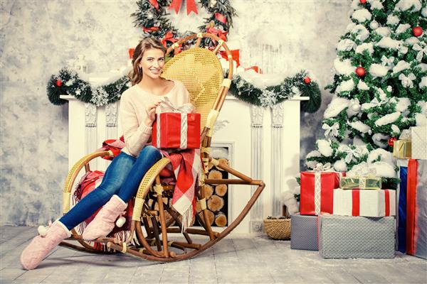مدل زن که کریسمس را در خانه کنار یک شومینه جشن می گیرد