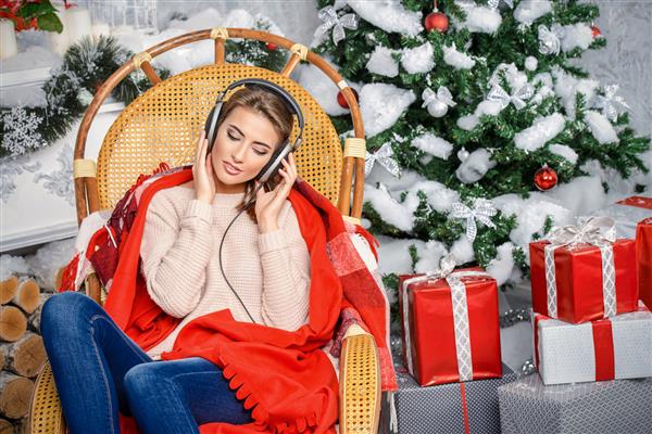 دختر زیبا از گوش دادن به موسیقی کریسمس در خانه لذت می برد