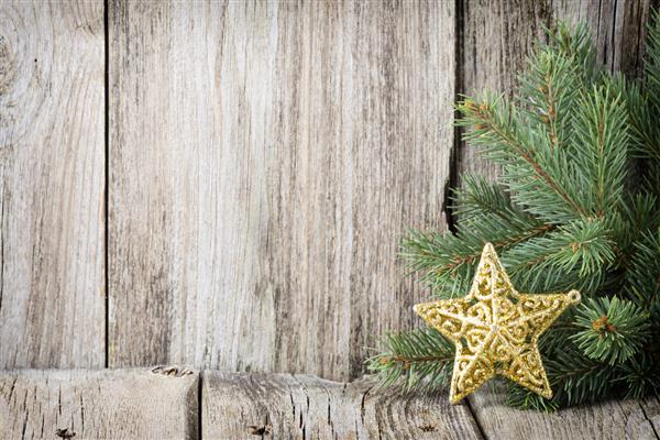 دکوراسیون کریسمس با شاخه های صنوبر در پس زمینه چوب