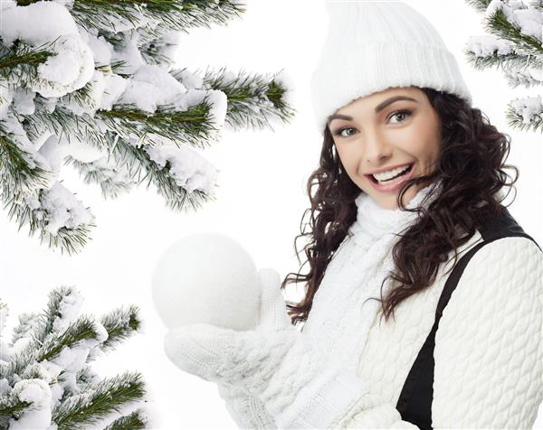 مدل زن با لباس گرم و خندان در کنار درخت کریسمس