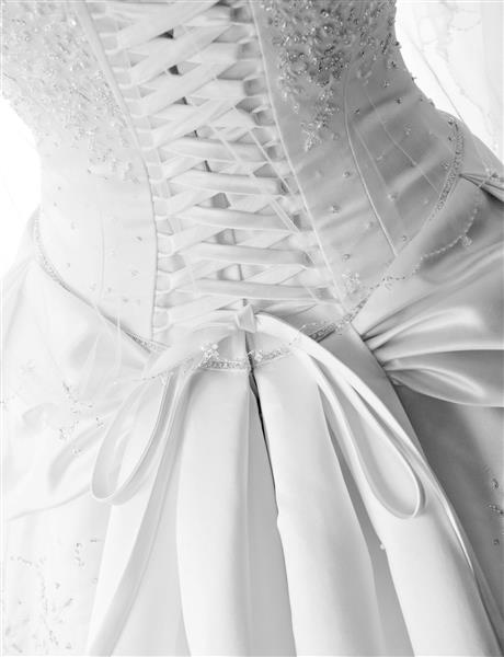 تصویری از نمای نزدیک از بندهای دقیق پشت لباس عروس