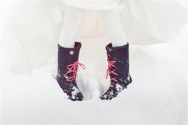 نمای نزدیک از عروس با چکمه های نمدی روی برف