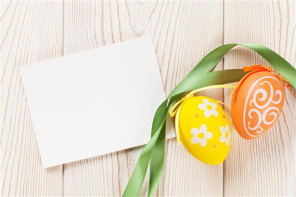 کارت تبریک عید پاک و تخم مرغ روی میز چوبی