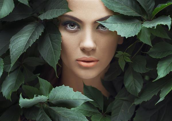 مدل زن احاطه شده با برگهای سبز