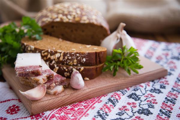 غذاهای ملی اوکراین نان قهوه ای تکه های گوشت روی سفره گلدوزی شده روی میز چوبی