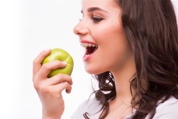 دختر جوان سیب می خورد دندان های زن با بریس تغذیه سالم با بریس