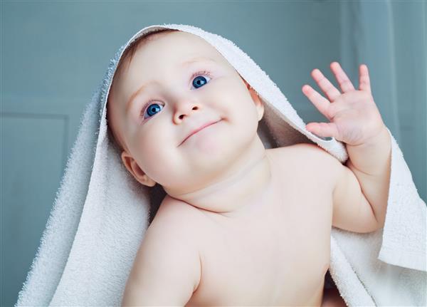 کودک شش ماهه با حوله بعد از حمام در رختخواب در خانه