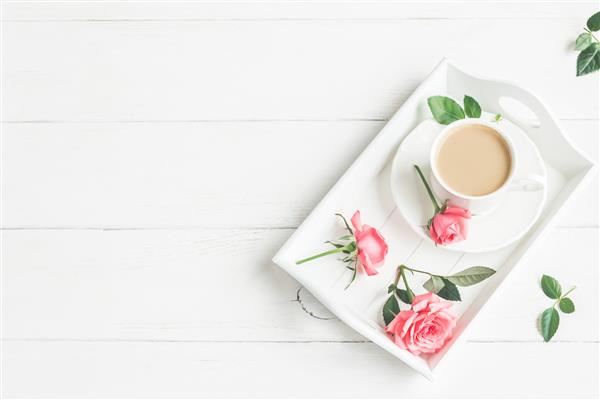 صبح فنجان قهوه و گلهای گل رز نمای بالا