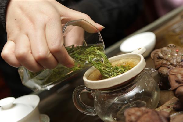 یک زن در بازار پکن چای چینی را فیلتر می کند