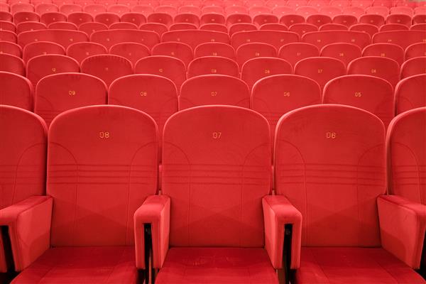 صندلی شماره 7 سالن نمایش خالی سینما با خطوطی از صندلی های قرمز