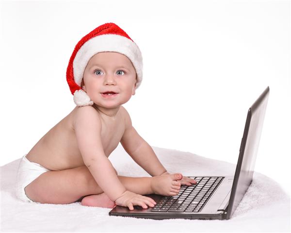 پرتره یک پسر جوان در کامپیوتر با کلاه سانتا پوشک لبخند