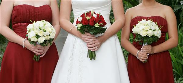 نمای نزدیک از یک عروس و ساقدوش های او دسته های زیبایی در دست دارند