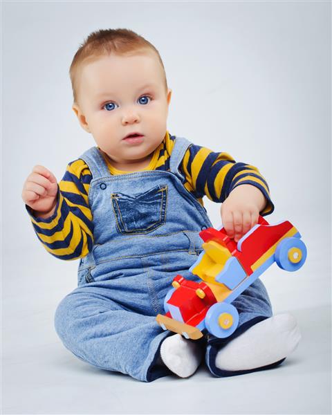 نوزاد پسر در حال بازی با ماشین اسباب بازی خود