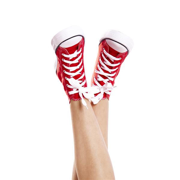 از نزدیک پاهای زن که یک جفت کفش کتانی قرمز رنگ بهمراه سفید پوشیده اند
