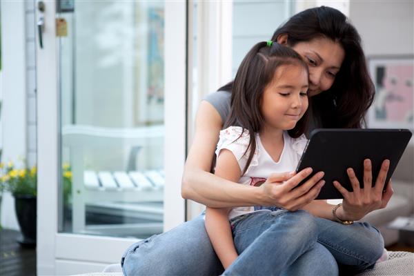 مادر و دختر در حال تفریح ​​با یک تبلت دیجیتال در فضای داخلی خانه