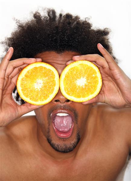مرد جوانی که پرتقال را جلوی چشمانش گرفته است
