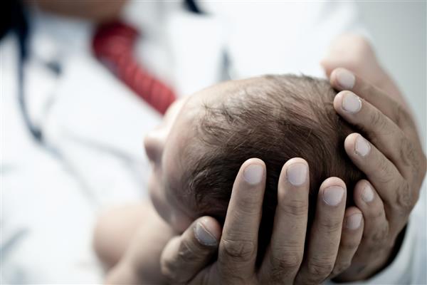 متخصص اطفال که یک نوزاد پسر زیبا و تازه متولد شده را در دست دارد